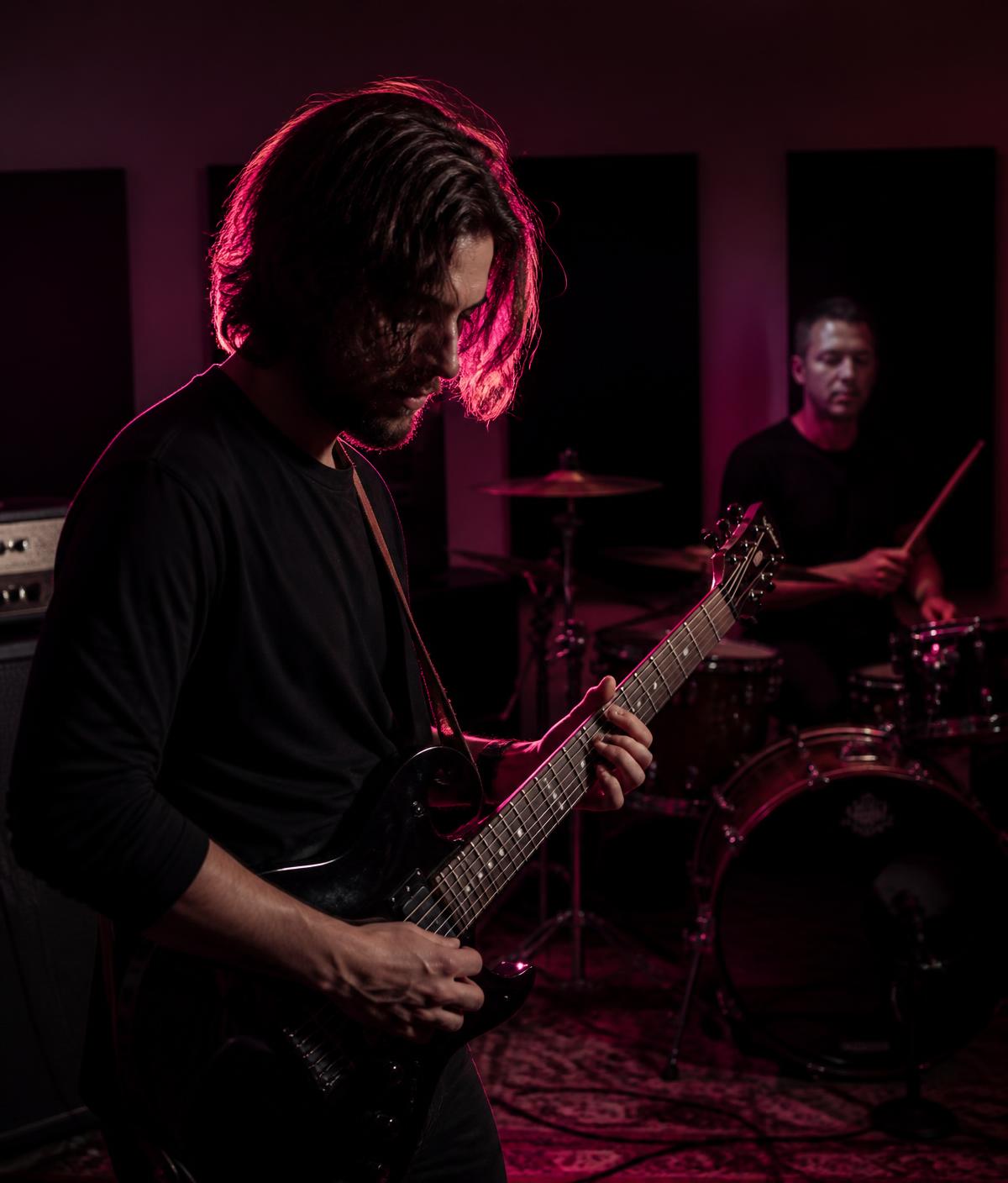 Banda ensaiando em estúdio com iluminação magenta